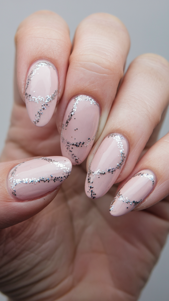 Simple and elegant nails with small silver glitter dots and lines on a pale pink base.
