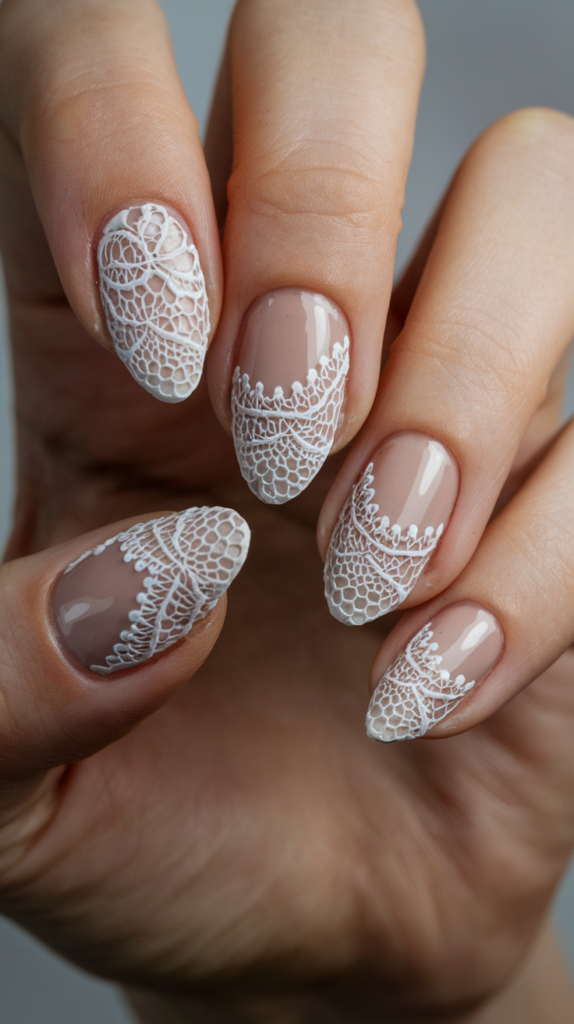 Intricate lace-patterned acrylic nails with delicate white designs over a nude base, creating an elegant and romantic look with fine detailing.

