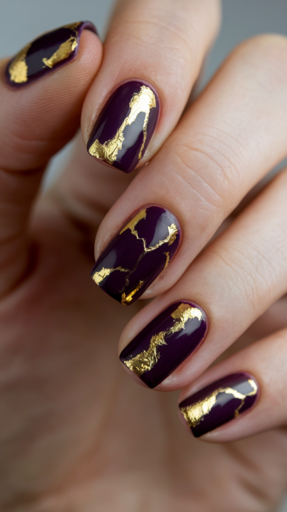 Deep purple nails with gold foil and accent lines, creating a luxurious, regal design.
