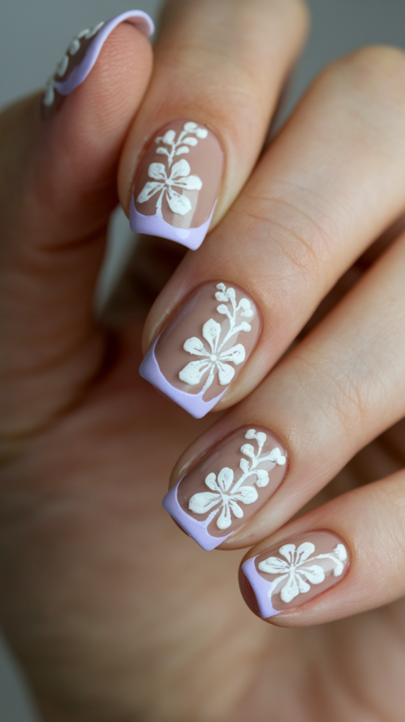 Nails with lavender French tips adorned with delicate white floral patterns