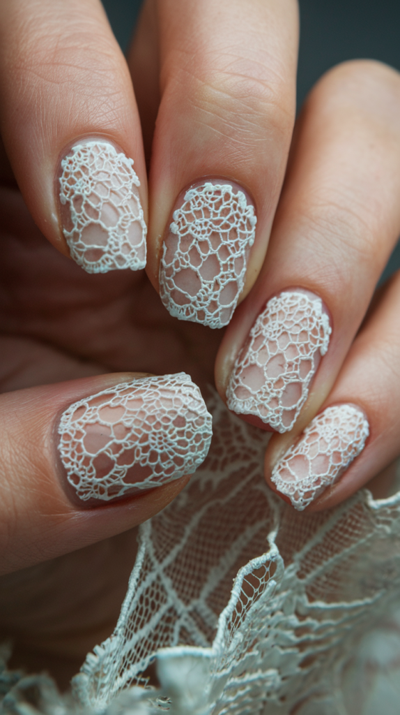 Nails with intricate, lace-like patterns painted in white over a pastel base of blush pink or lavender, creating a soft, romantic look.