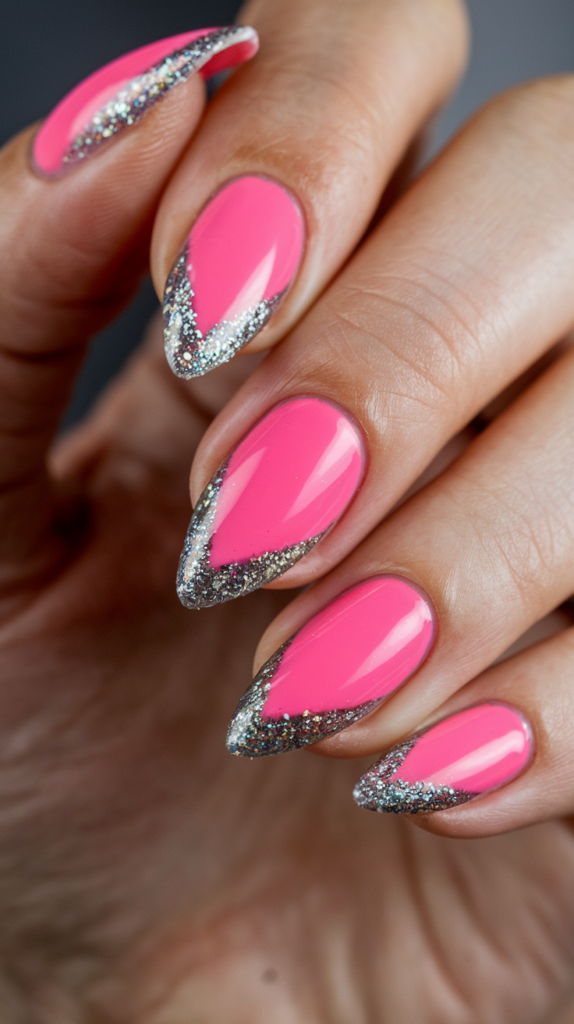 Sharp stiletto-shaped nails painted pink with glitter tips, offering a dramatic and glamorous look