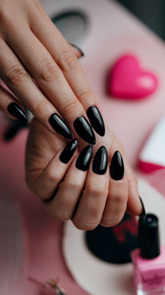 Long, sleek almond-shaped stiletto nails painted in solid black, emphasizing an elegant and dramatic look