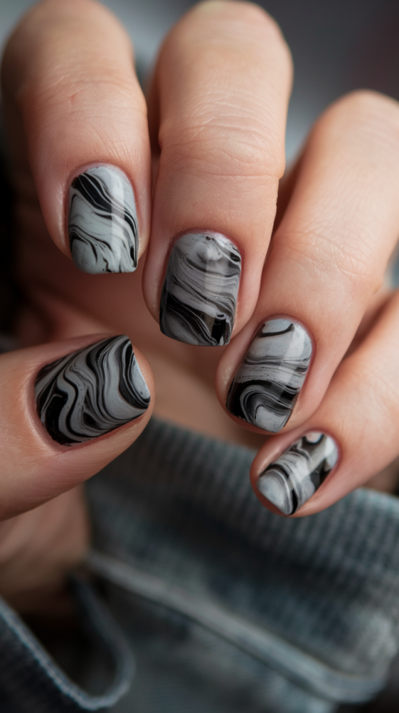 Artistic black and gray marble effect on nails, mimicking the natural elegance of stone with swirling patterns