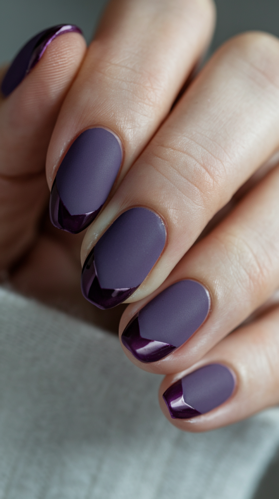 Dark purple matte nails with small, sparkling rhinestones near the cuticles