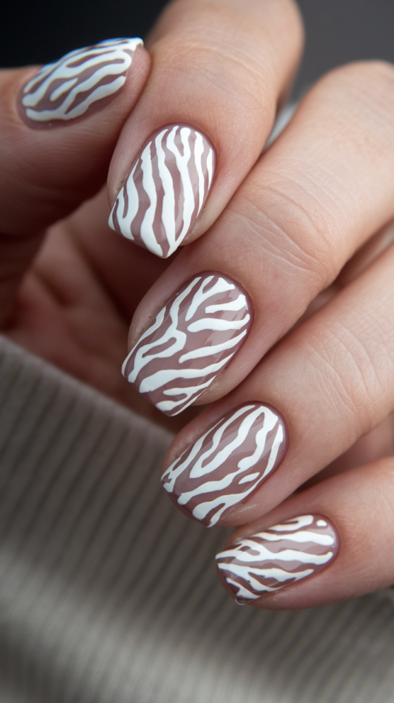 Bold white zebra print on nude nails for a trendy animal print look.
