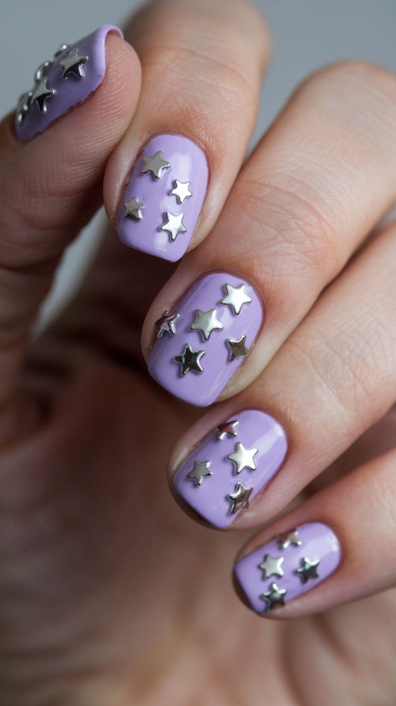 Pale purple nails adorned with tiny metallic or glittering star accents for a celestial look.
