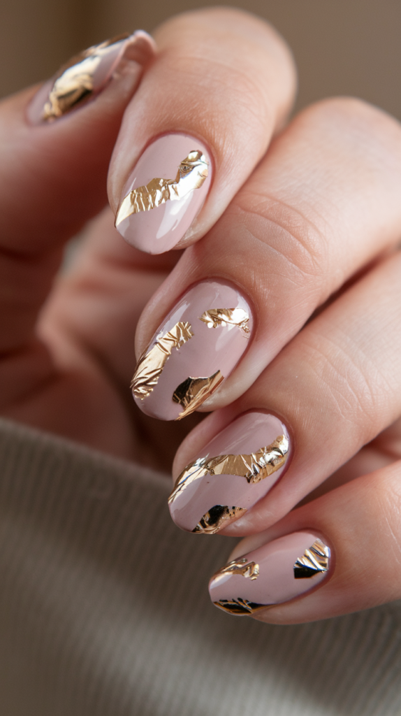 Soft pink nails accented with luxurious gold foil, creating a high-end, textured finish