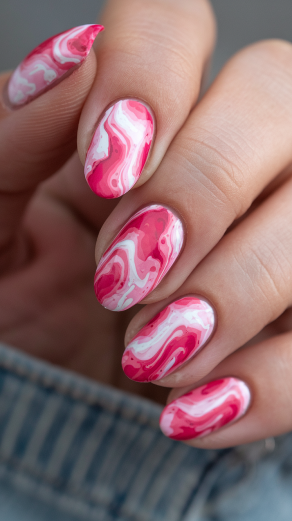 Groovy pink tie-dye nails with swirling patterns of pink, white, and purple for a retro vibe