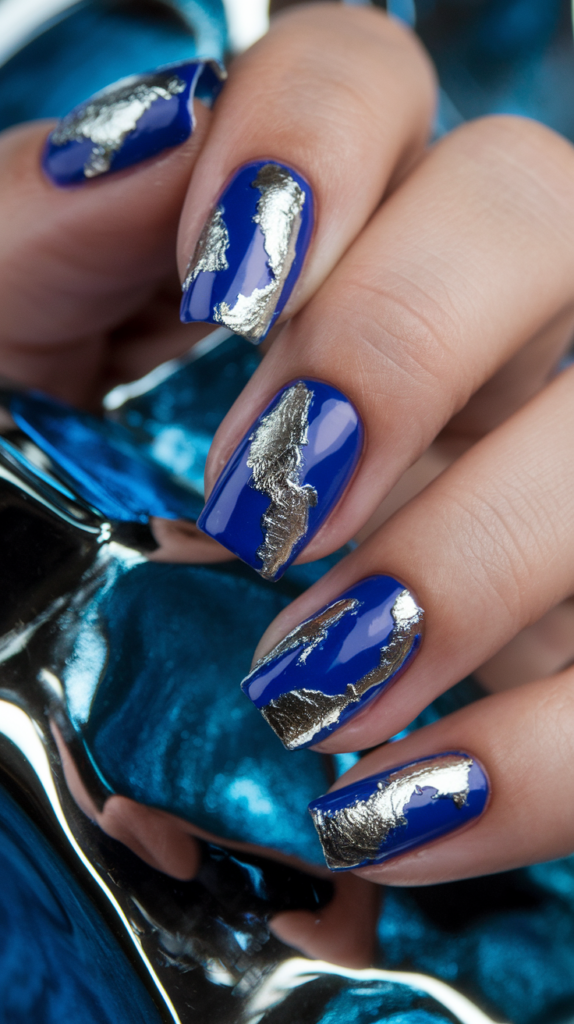 Cobalt blue nails with random pieces of silver foil applied to create a bold, edgy design