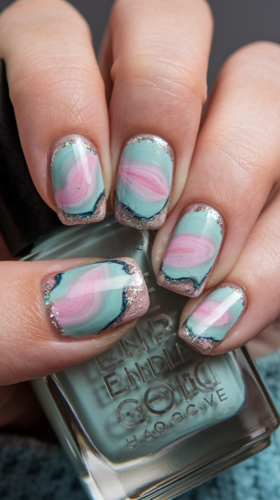 Nails with a geode-inspired design, featuring irregular shapes in pastel shades like mint green and lavender, outlined with gold metallic accents.