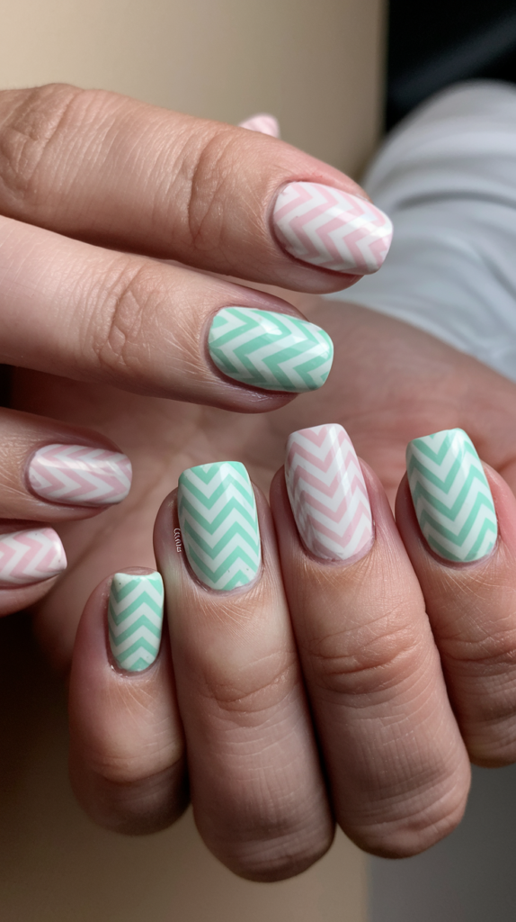 Nails with zig-zag chevron stripes in alternating pastel shades like mint green and soft pink, creating a clean and stylish pattern.