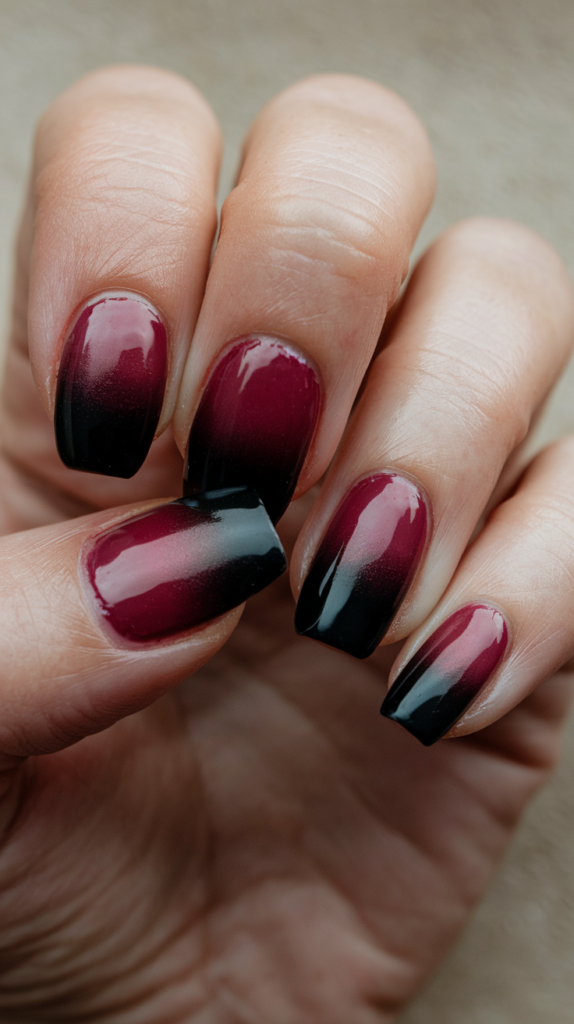 Bold, moody nails with a seamless gradient from deep black to rich burgundy, perfect for fall or winter looks.