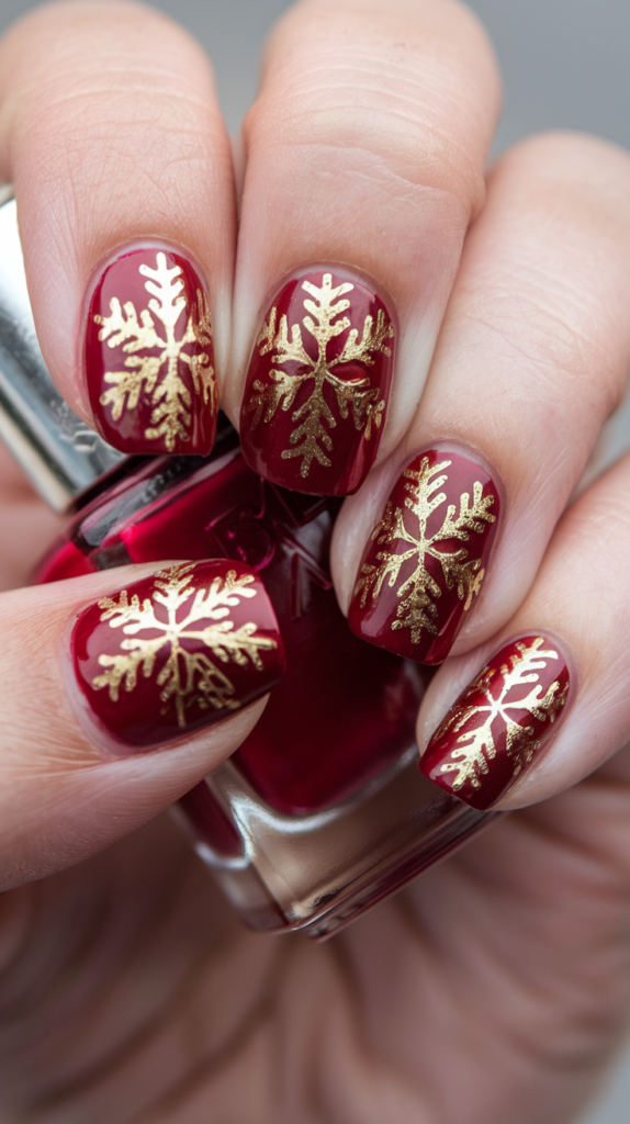 Nails featuring intricate golden snowflakes on a deep red base, exuding a luxurious holiday vibe