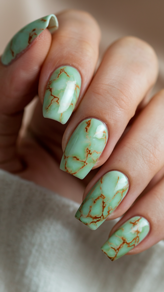 Nails with a jade-inspired marble design in soft green with white veins