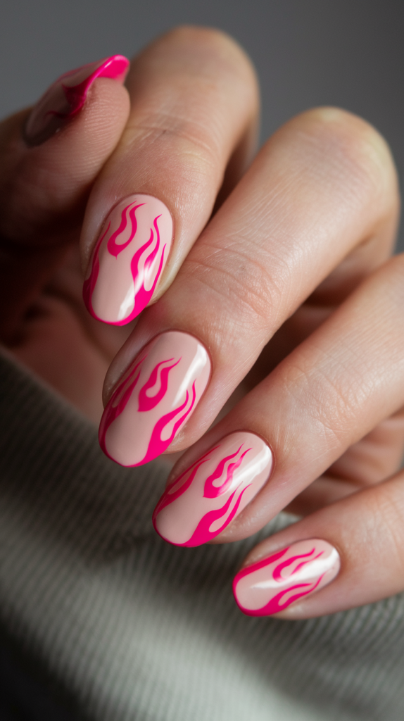 Nude nails with hot pink flames rising from the tips, adding an edgy, rebellious vibe.

