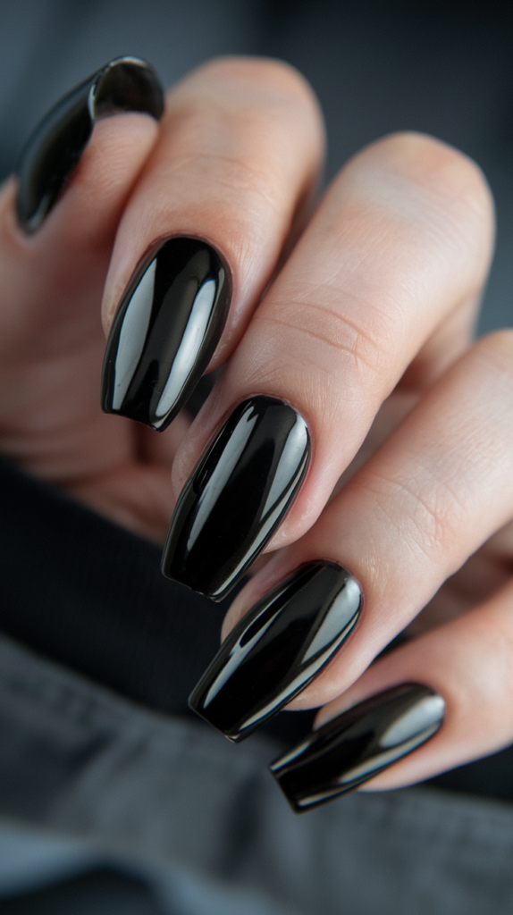 Sleek, glossy black coffin-shaped nails reflecting soft light