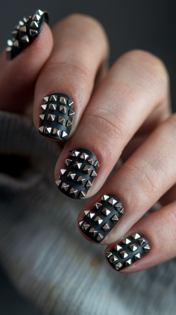 Steel-Studded Accents – Black nails with metallic steel studs arranged symmetrically near the cuticle.
