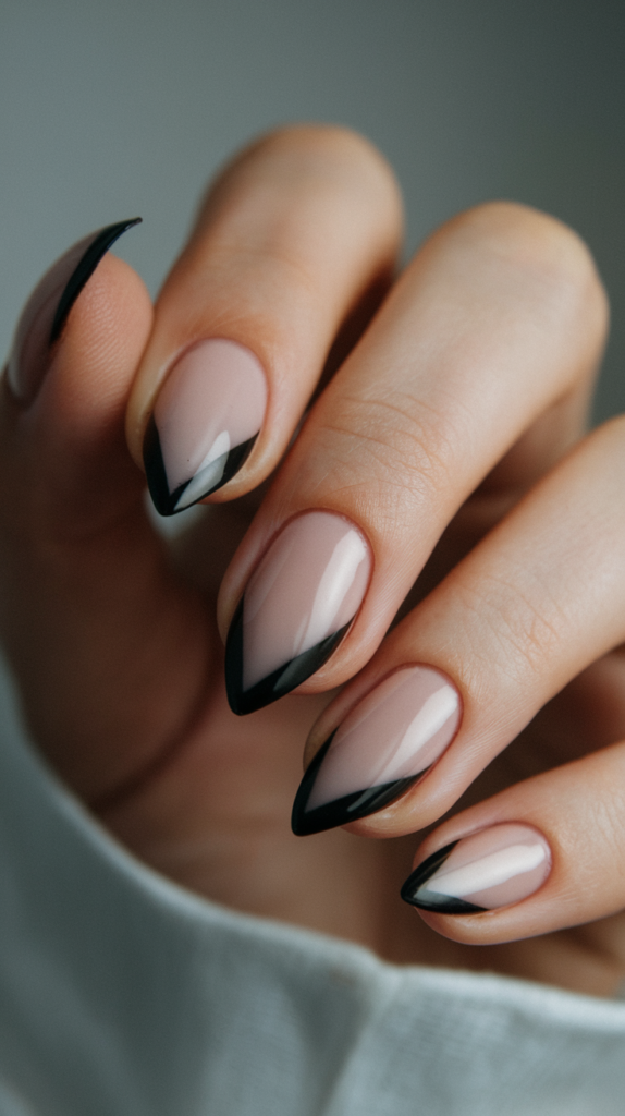 Nude nails with sharp black French tips in a matte finish