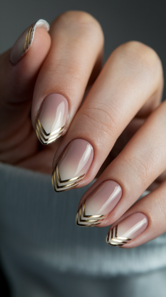 Soft ombré gradient nails with bold chevron gold accents, blending subtle gradients with sharp geometric patterns.
