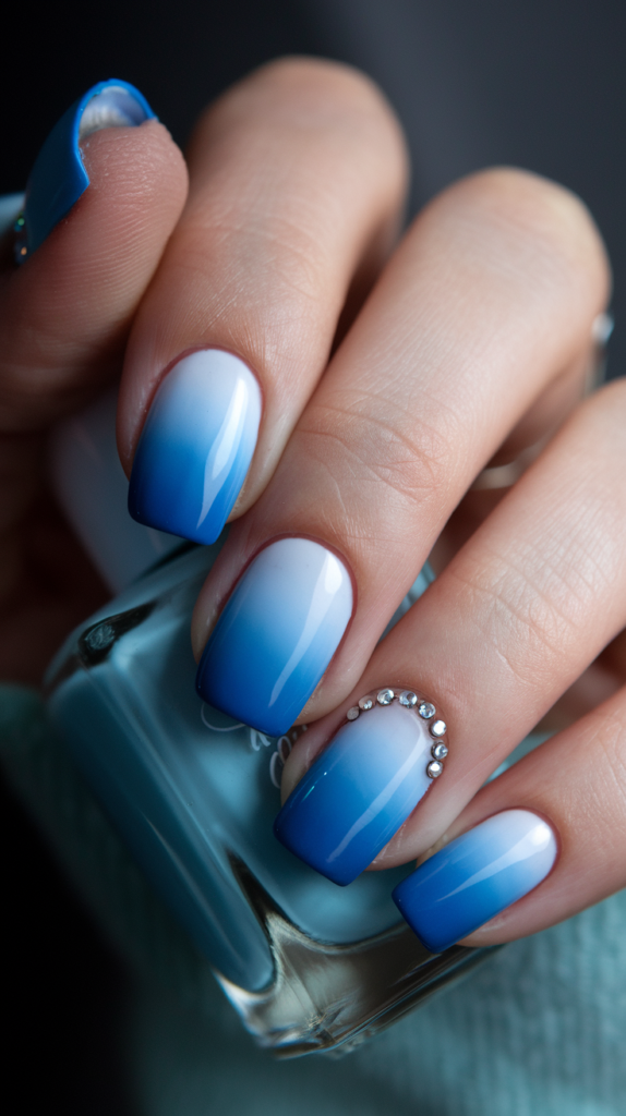 Blue Ombre with Rhinestones – Ombre nails with rhinestone accents near the cuticle.
