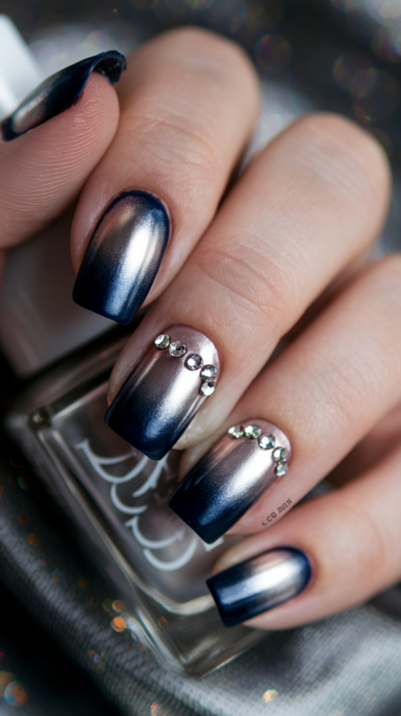 Ombre nails transitioning from deep navy to metallic silver, accented with rhinestones for a glamorous look.
