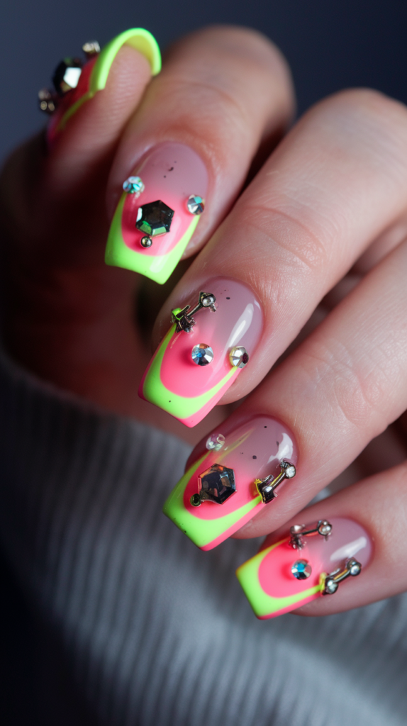 Neon nail art with 3D accents, featuring rhinestones and studs on a pink and yellow base