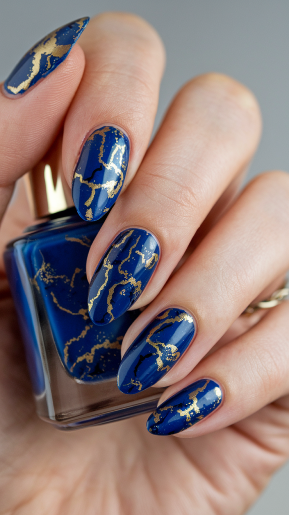 Royal blue nails with intricate gold marbling, creating a regal, marble-like effect that exudes sophistication