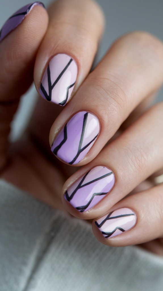 Nails painted in various violet tones, arranged in bold, geometric shapes, giving an edgy, modern style.