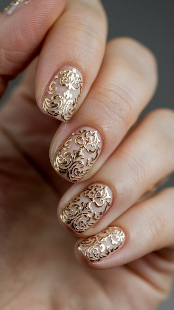 Nude nails with intricate, vintage-style gold filigree patterns for a timelessly regal appearance.

