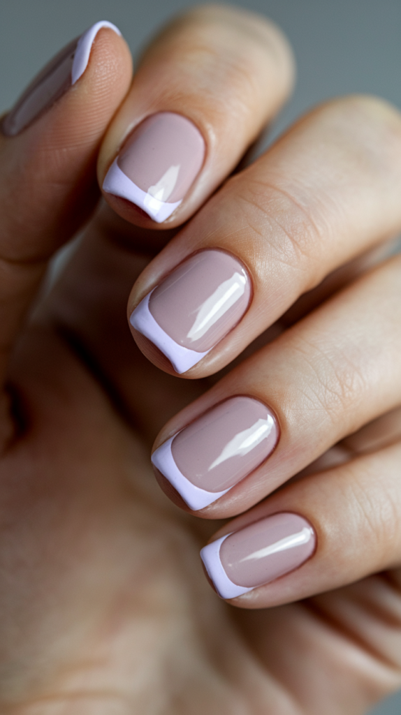 A classic French manicure style with light lavender tips, set on a clear, nude base for a chic and modern look.