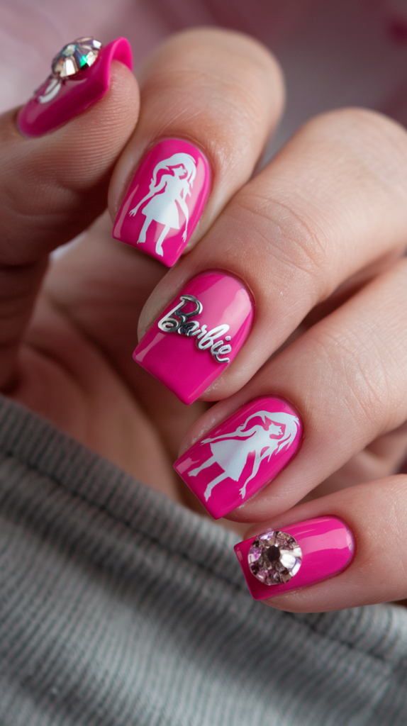 Hot pink nails featuring Barbie silhouettes in black, glittery rhinestone embellishments, and an ombre effect with glossy finishes.