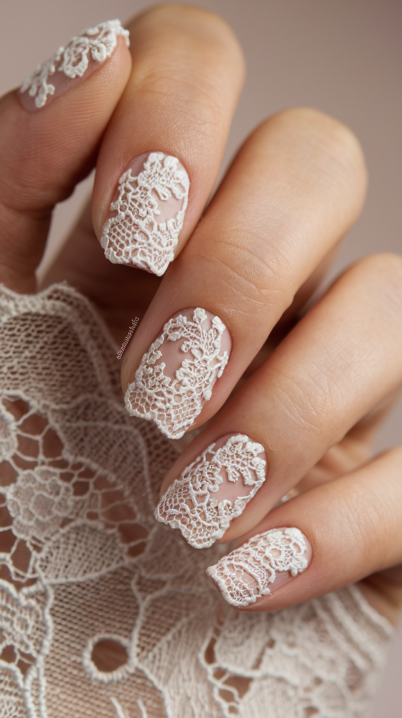 Nude nails with intricate white lace patterns, giving a delicate, wedding-inspired look.

