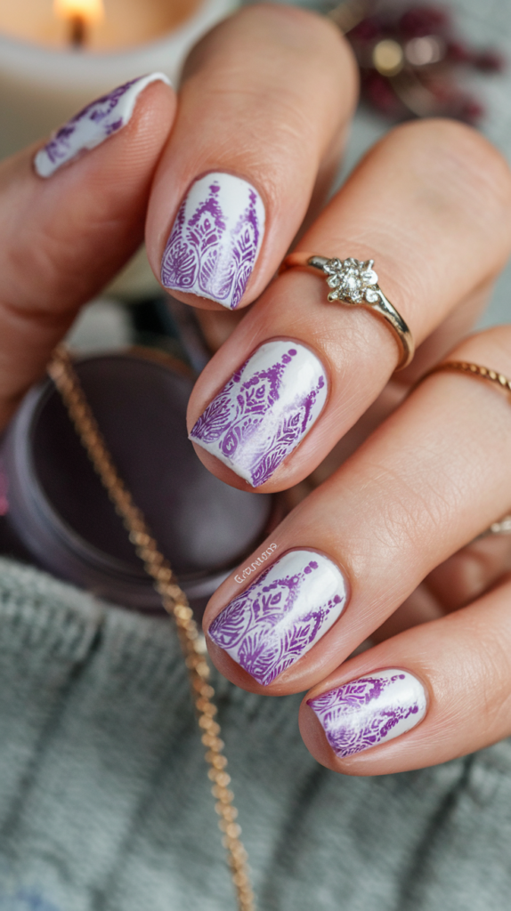 Nails with a pale lavender base stamped with a gradient pattern in multiple violet hues, creating intricate designs.

