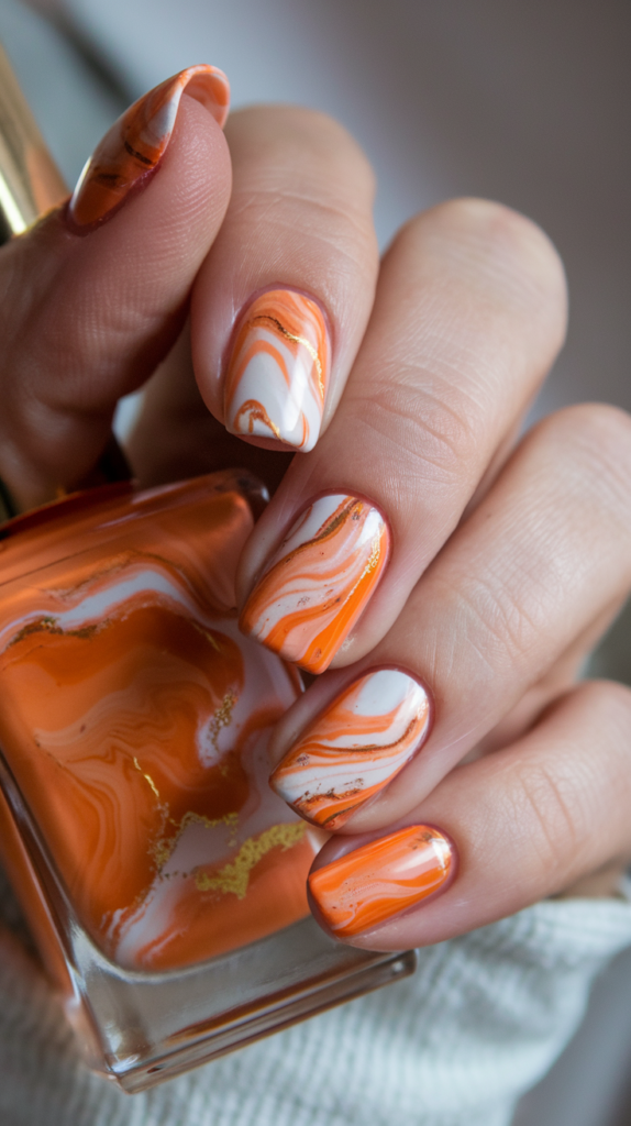 Swirled orange, white, and gold marble nails for an elegant, coral-inspired design.
