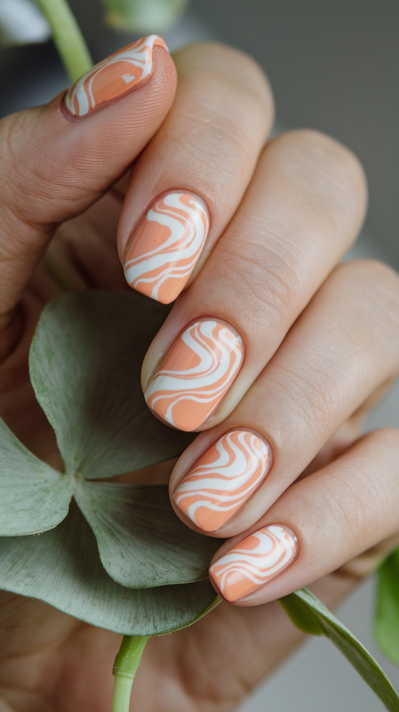 Spooky Halloween-themed orange nails featuring bats, webs, and pumpkin faces.
