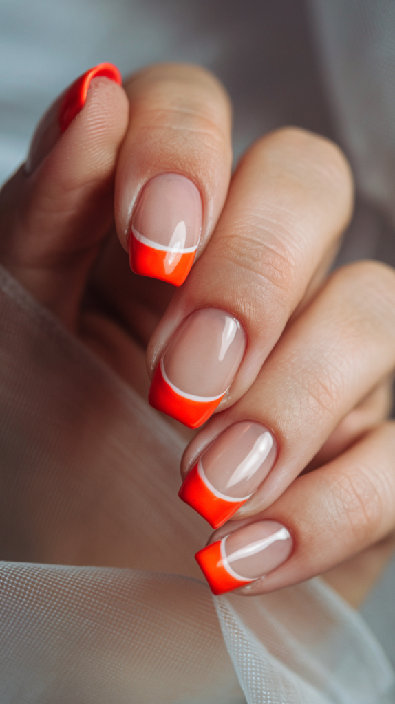 Classic French manicure with bright orange tips for a playful twist on a timeless style.
