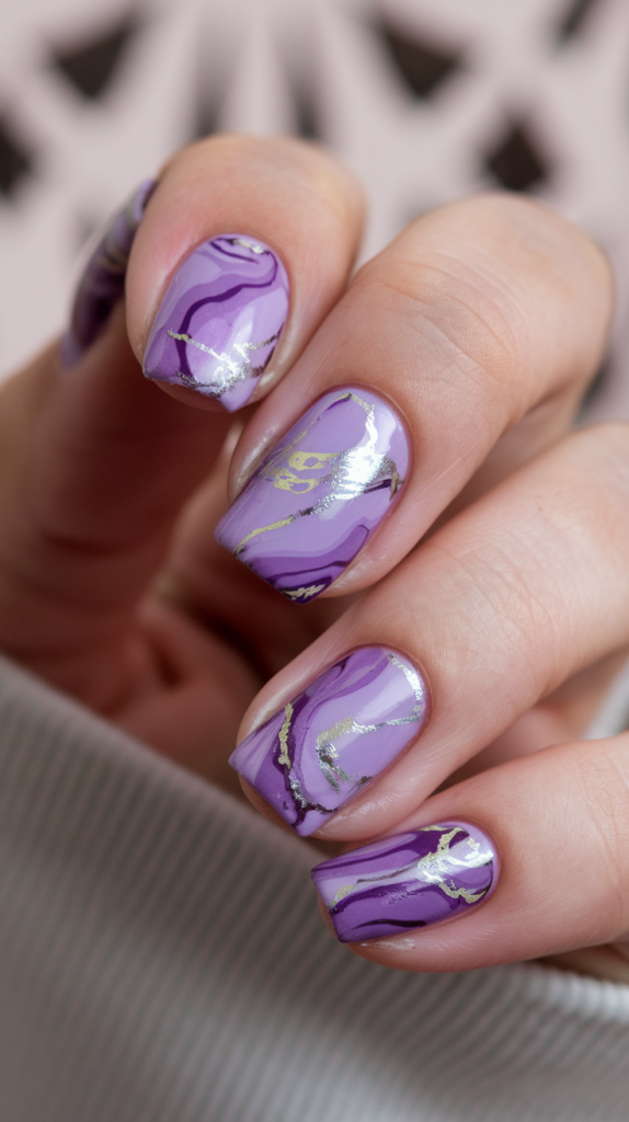 Marbled violet nails with silver foil accents, resembling polished marble with a luxurious touch.

