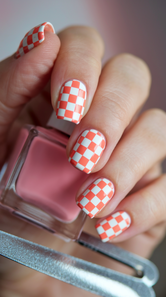 Trendy orange and white checkerboard pattern on nails for a fun, stylish look.
