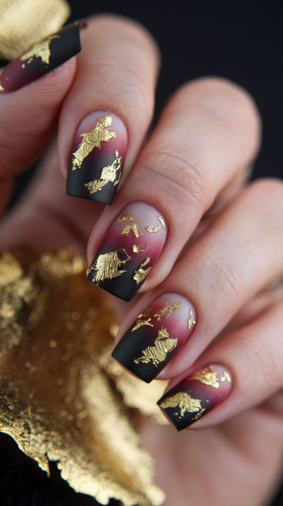 Matte black nails with delicate gold leaf accents near the tips, creating a luxurious and elegant New Year’s look with rich, warm tones