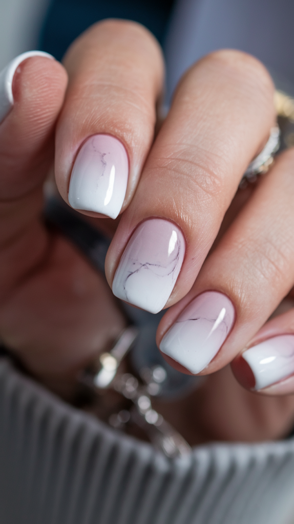 Soft white to gray gradient nails with subtle marble-like veins and a glossy finish.